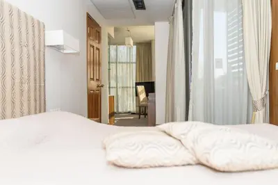 a bedroom with a white bed and a living room at Hotel Burgas in Burgas City