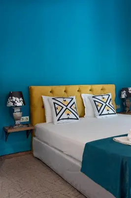 a bed with a blue wall and pillows on it at Royal Calisto Hotel in Sozopol