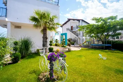 a white bike parked in a yard with flowers at Royal Calisto Hotel in Sozopol