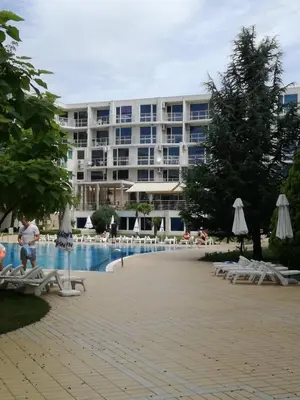 a hotel with a pool and chairs and a building at Apartament Ivanovi A119 in Burgas City