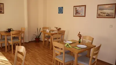 a dining room with wooden tables and chairs at Hotel Palitra in Varna City