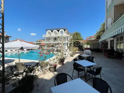 a patio with tables and chairs next to a pool at Hotel Onyx in Kiten