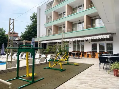 a playground in front of a building with tables and chairs at Hotel Onyx in Kiten