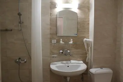 a bathroom with a sink and a toilet and a mirror at Hotel Onyx in Kiten