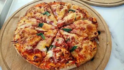 a pizza sitting on top of a wooden cutting board at Aquamarine Hotel - All Inclusive in Sunny Beach