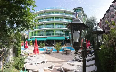a hotel with chairs and umbrellas in front of a building at Hotel L&B- Free parking in Sunny Beach
