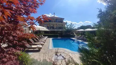 a swimming pool with lounge chairs and a building at Family Hotel Muses in Sozopol