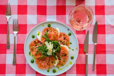 a plate of food with tomatoes and greens on a table at Effect Grand Victoria Hotel - Ultra All Inclusive in Sunny Beach