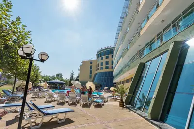 a group of lounge chairs and tables next to a building at Ivana Palace Hotel - Free Parking in Sunny Beach
