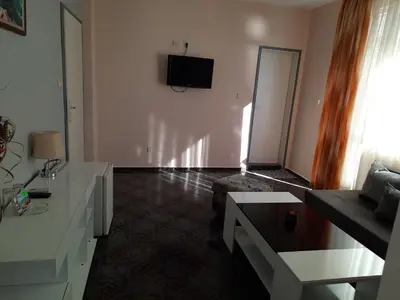a living room with a couch and a tv on the wall at ORION Guest House in Sozopol