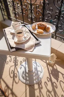 a table with two cups of coffee and a plate of donuts at Hotel Zeus in Pomorie