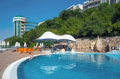 a swimming pool with tables and chairs and an umbrella at Paradise Beach Residence - Ultra All Inclusive in Sveti Vlas