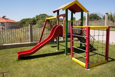 a playground with a slide in the grass at Gardenia Vacation Settlement in Sozopol