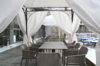 a patio with tables and chairs and white curtains at Smartline Meridian Hotel in Sunny Beach