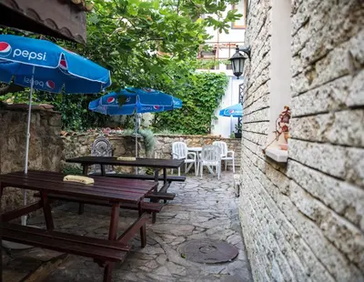 a patio with two wooden tables and an umbrella at Victoria Hotel Nessebar in Nesebar