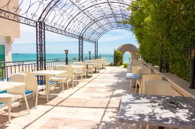 an outdoor patio with tables and chairs and an archway at Bilyana Beach Hotel- Adults only in Nesebar