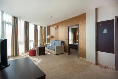 a living room with a couch and a chair in a hotel room at Hotel Primorsko Del Sol in Primorsko