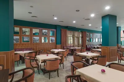 a dining room with tables and chairs and green walls at Hotel Primorsko Del Sol in Primorsko