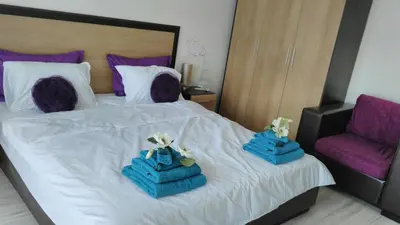 a bed with two blue boxes on it with a chair at Villa Bonita Apartment in Sunny Beach