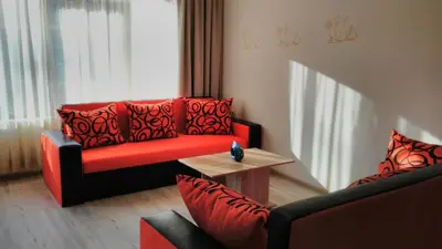 a living room with two chairs and a red couch at Villa Bonita Apartment in Sunny Beach