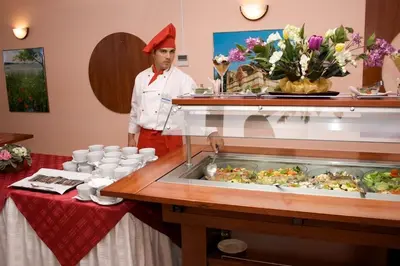 a chef standing in front of a buffet with food at Dunav Hotel in Sunny Beach