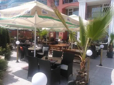 an outdoor restaurant with tables and chairs and umbrellas at Carina Beach in Sunny Beach