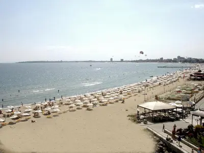 a beach with umbrellas and people in the water at Carina Beach in Sunny Beach