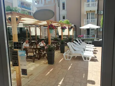 a patio with white chairs and tables and people sitting at tables at Tropics Hotel - Ultra All Inclusive in Sveti Vlas