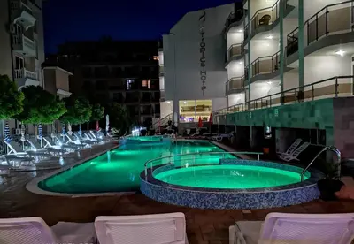 a swimming pool in front of a building at night at Tropics Hotel - Ultra All Inclusive in Sveti Vlas