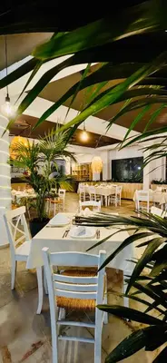 a restaurant with white tables and chairs and plants at iHotel Sunny Beach in Sunny Beach