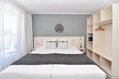 a white bedroom with a large bed and a window at iHotel Sunny Beach in Sunny Beach