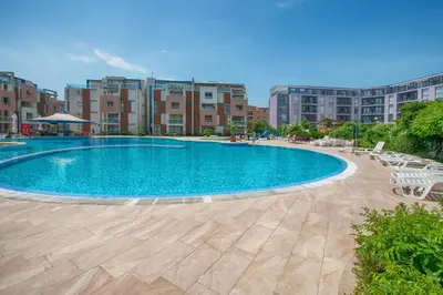 a large swimming pool with chairs and buildings in the background at Sun City I Apartments in Sunny Beach