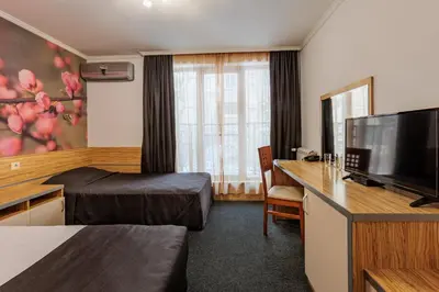 a hotel room with a bed and a flat screen tv at Семеен Хотел Опера in Burgas City