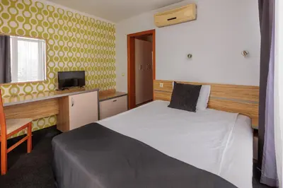a hotel room with a bed and a desk at Семеен Хотел Опера in Burgas City