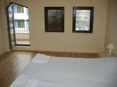a bedroom with a large white bed with two windows at Sozopol Dreams Apartments in Sozopol