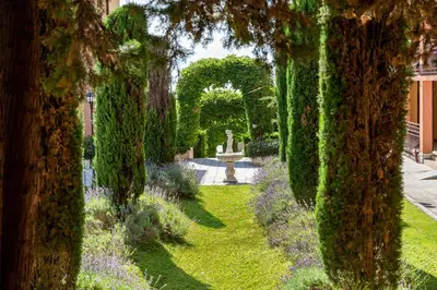 a garden with an arch and a fountain and trees at Galeria Holiday Apartments in Obzor