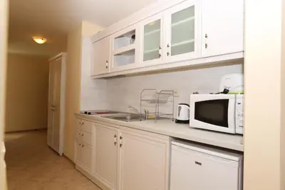 a kitchen with white cabinets and a microwave at Galeria Holiday Apartments in Obzor