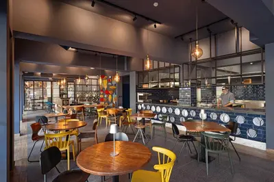 a restaurant with wooden tables and yellow chairs at Zefir Hotel in Sunny Beach