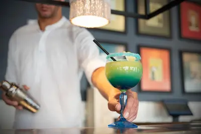 a man is holding a blue drink on a table at Zefir Hotel in Sunny Beach