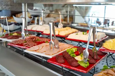 a buffet line of food with tongs and meats at MPM Hotel Arsena - Ultra All Inclusive in Nesebar