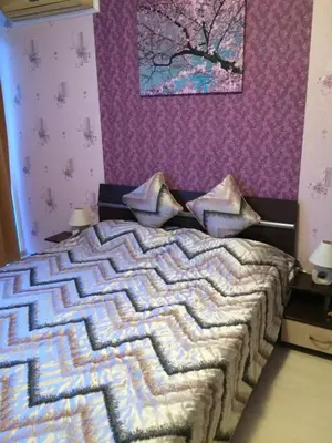 a bedroom with a bed with a purple wall at Apartment Sianie в центъра на Слънчев бряг, само на няколко крачки от плажа in Sunny Beach