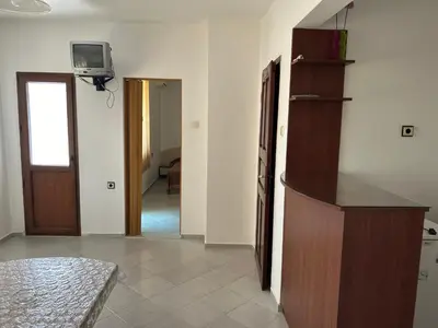 a living room with a kitchen and a tv on the wall at КЪЩА
