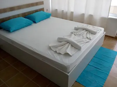 a bed with white sheets and blue pillows on it at Studio Zlatina in Pomorie