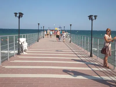 a woman standing on a pier near the ocean at Family Hotel Romantik in Sunny Beach