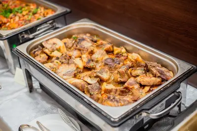 a pan filled with meat and vegetables on a stove at Deva Hotel - All Inclusive in Sunny Beach