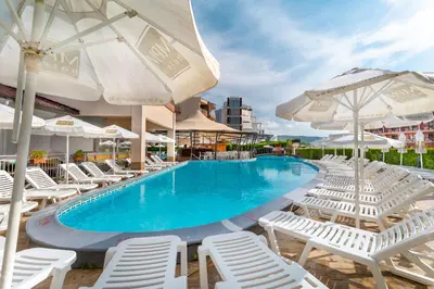 a swimming pool with white lounge chairs and umbrellas at MPM Astoria Hotel - Ultra All Inclusive in Sunny Beach