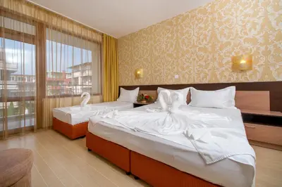 a hotel room with two beds and a window at Hotel Iris in Nesebar