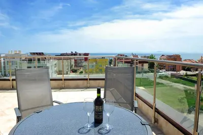 a table with two glasses of wine on a balcony at Hotel Iris in Nesebar