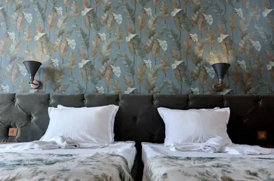 a bedroom with two beds and a wall with a floral wallpaper at Hotel Avenue in Sunny Beach