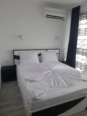 a bedroom with a bed with white sheets and pillows at Guest House Evtimov in Primorsko